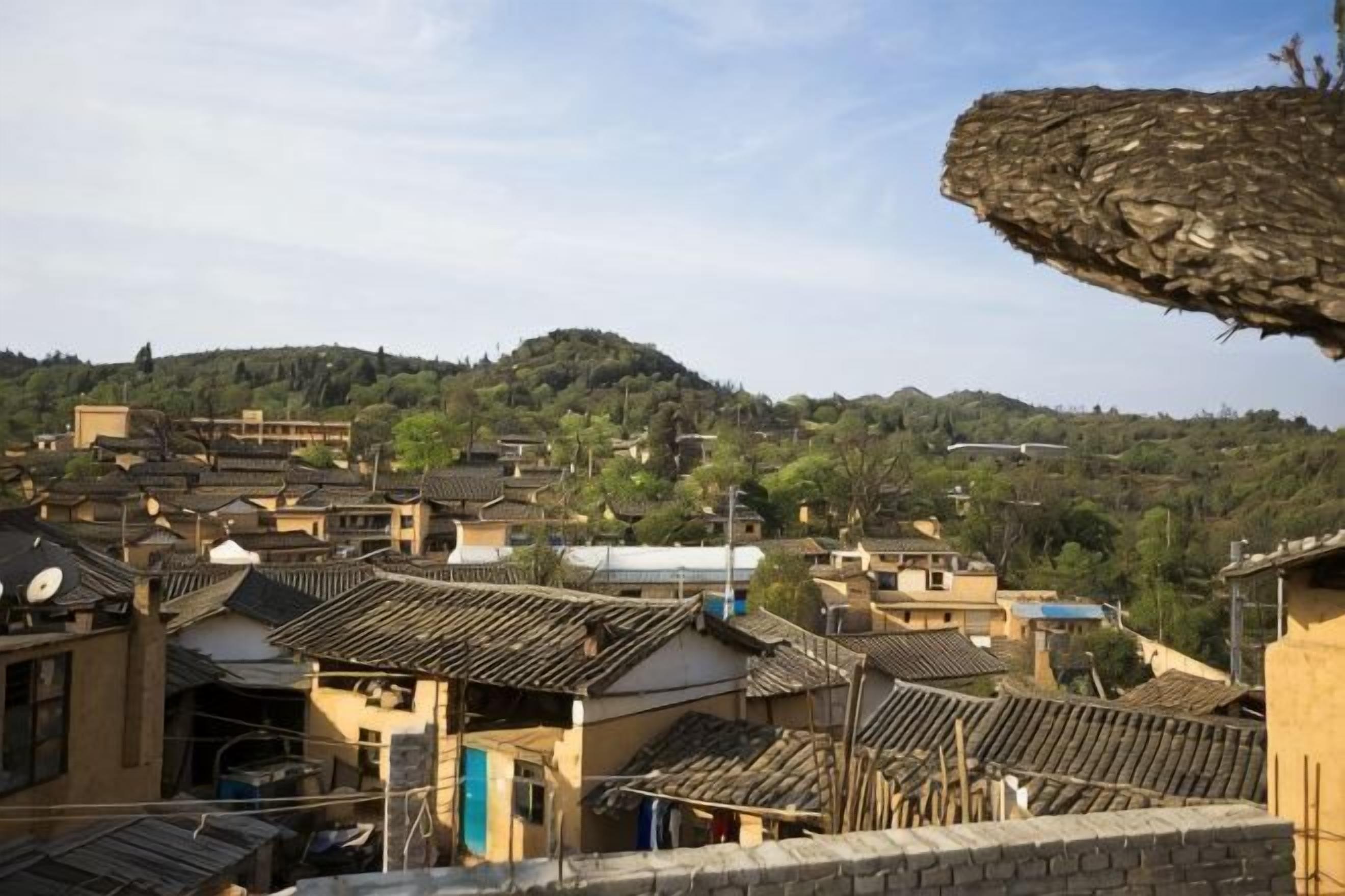 Un pueblo tradicional con edificios de techo de paja y un paisaje montañoso al fondo.