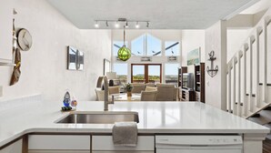 Een moderne keuken met een groot eiland, een ingebouwde vaatwasser en een eethoek met uitzicht op de omgeving.