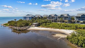 Ein Küstenhotel mit mehreren Gebäuden, einem Steg und einem Strand.