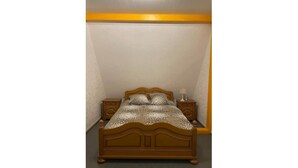 A small, single-bed room with a wooden headboard, two bedside tables, and a patterned bedspread. - Chalet-style house in the heart of nature (Kruth)