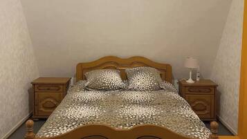 Een kleine kamer met een enkel bed, een houten hoofdeinde, twee nachtkastjes en een bed met een patroon.