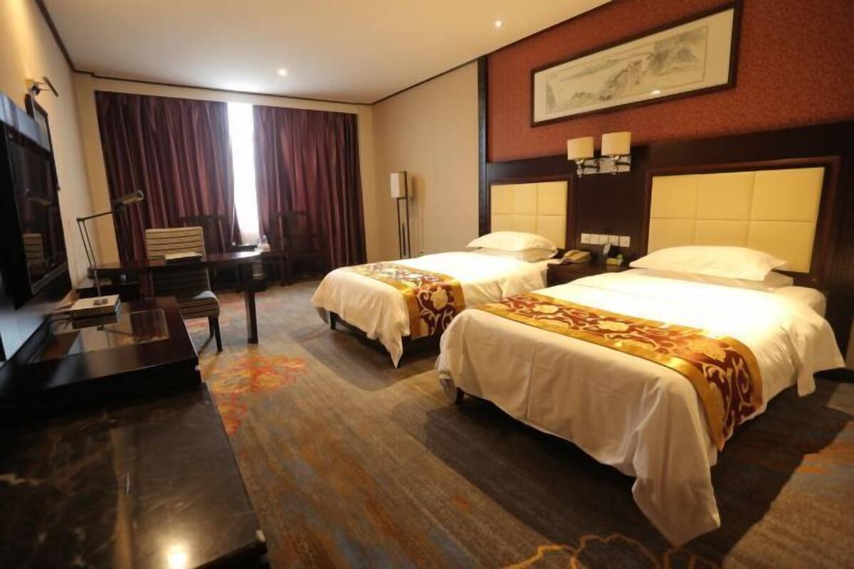 Habitación de hotel con dos camas, un escritorio y una silla.
