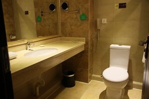 A bathroom with a sink, mirror, toilet, and trash bin. - Dihao Hotel (Xing'an County)