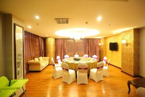 Uma sala de conferência com uma mesa redonda, cadeiras brancas e um lustre.