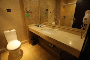A bathroom with a toilet, sink, mirror, and a trash bin. - Dihao Hotel (Xing'an County)