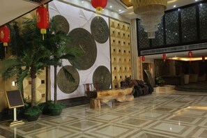 A lobby with a polished marble floor, decorative wall panels, and a wooden bench. - Dihao Hotel (Xing'an County)