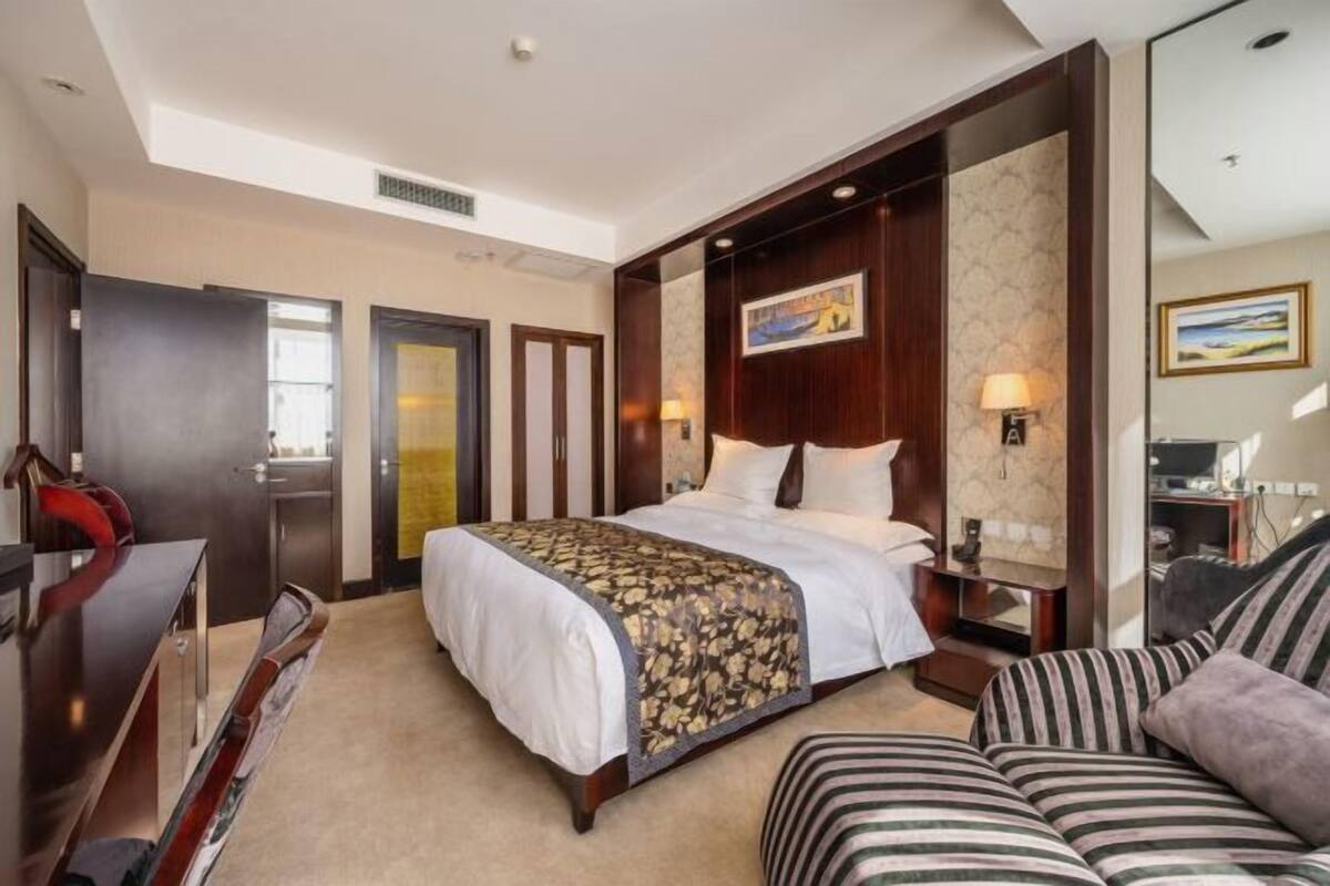 Habitació d'hotel amb un llit gran, un sofà, un escriptori i una televisió.