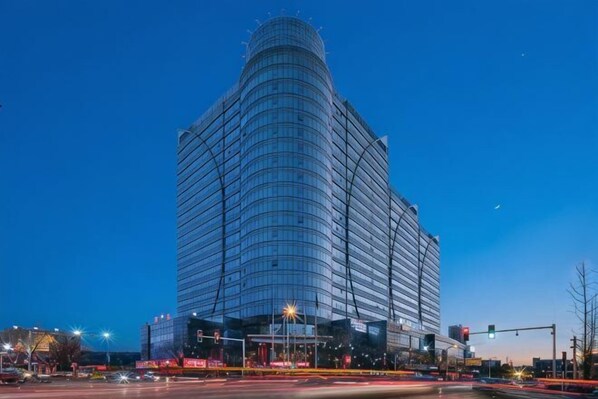 Un moderno edificio de gran altura con fachada curva, ventanas amplias y una entrada destacada.