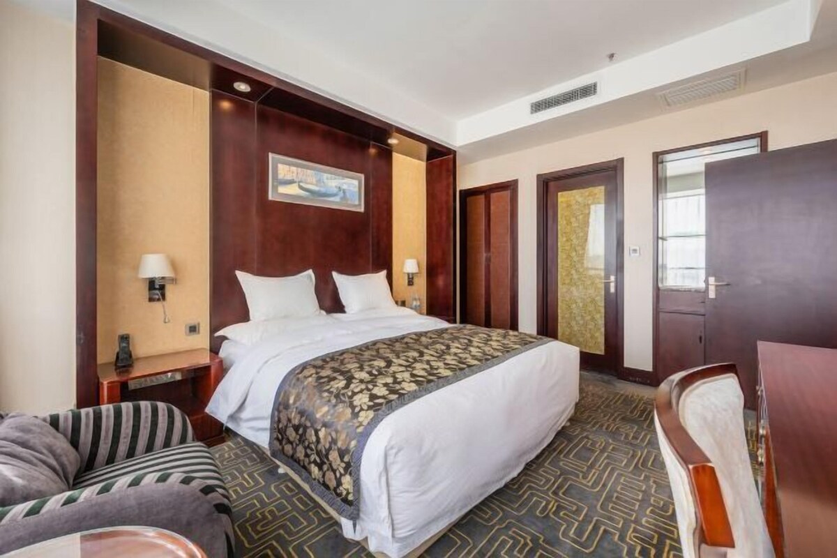 A hotel room with a large bed, two bedside tables, a desk, and a chair.