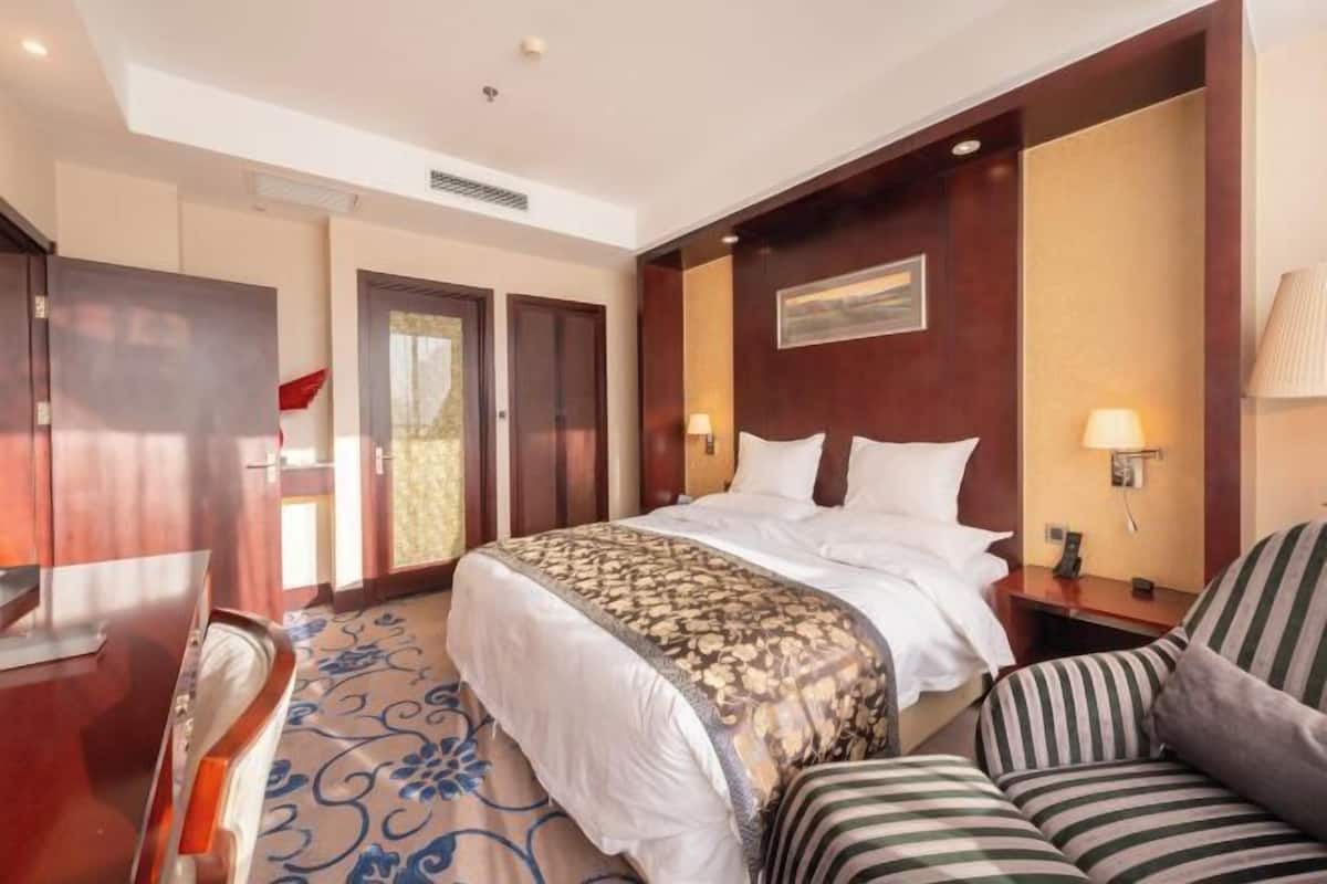 Habitació d'hotel amb un llit, una cadira, un escriptori i una porta.