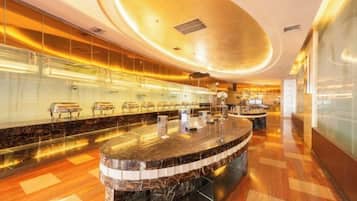 A modern hotel lobby with a curved reception desk, marble flooring, and a glass partition.