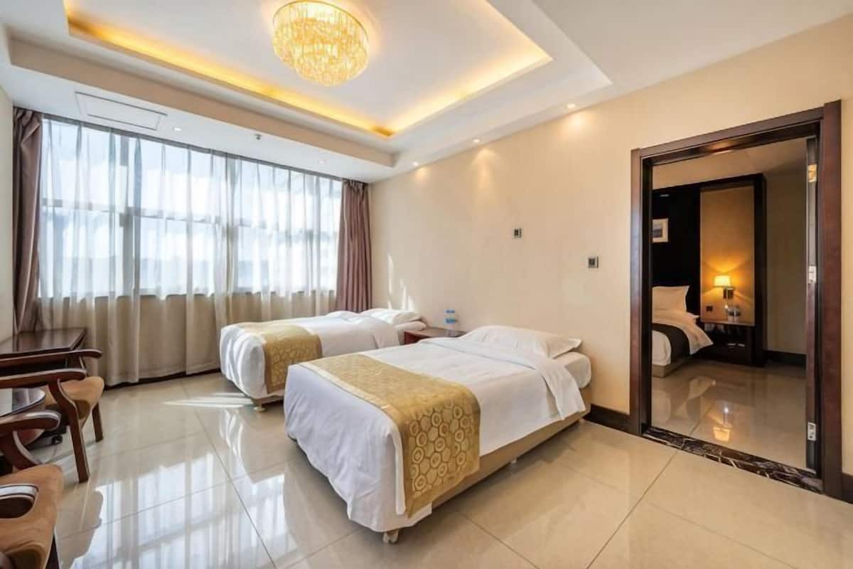Habitació d'hotel amb dos llits, un escriptori i un gran mirall.