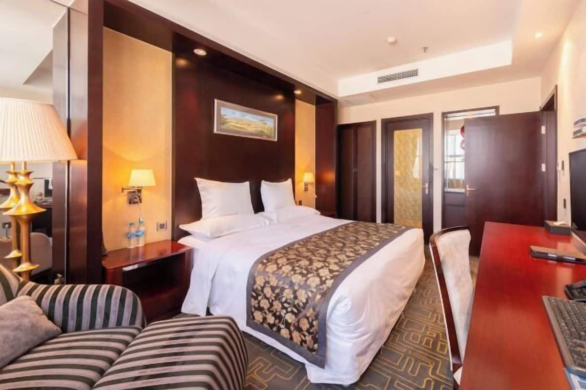 Habitació d'hotel amb un llit, un escriptori, una cadira, un sofà i una televisió.