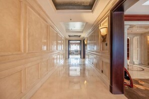 A long, polished hallway with a reflective floor, leading to a room with a large window and a chandelier. - Fugu Shanshuiyangguangjiudian (Fugu)