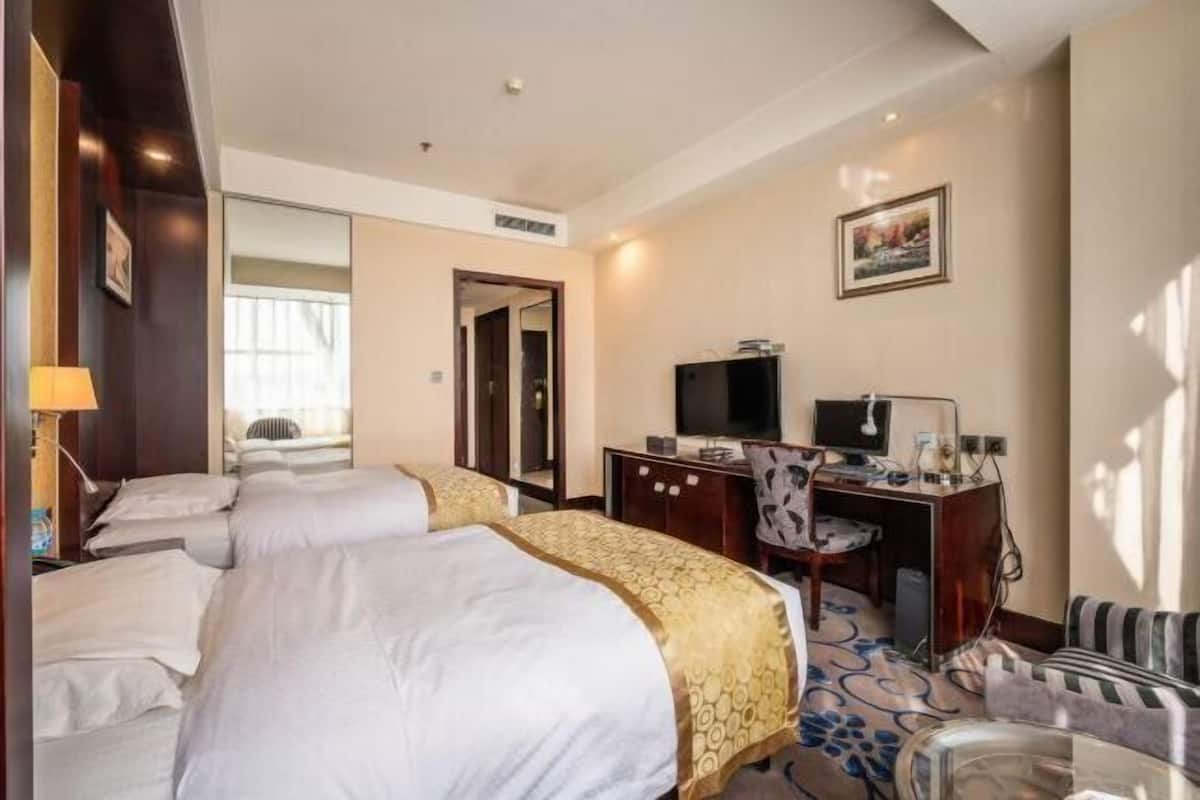 Habitació d'hotel amb dos llits, un escriptori amb un ordinador, una televisió i una cadira.