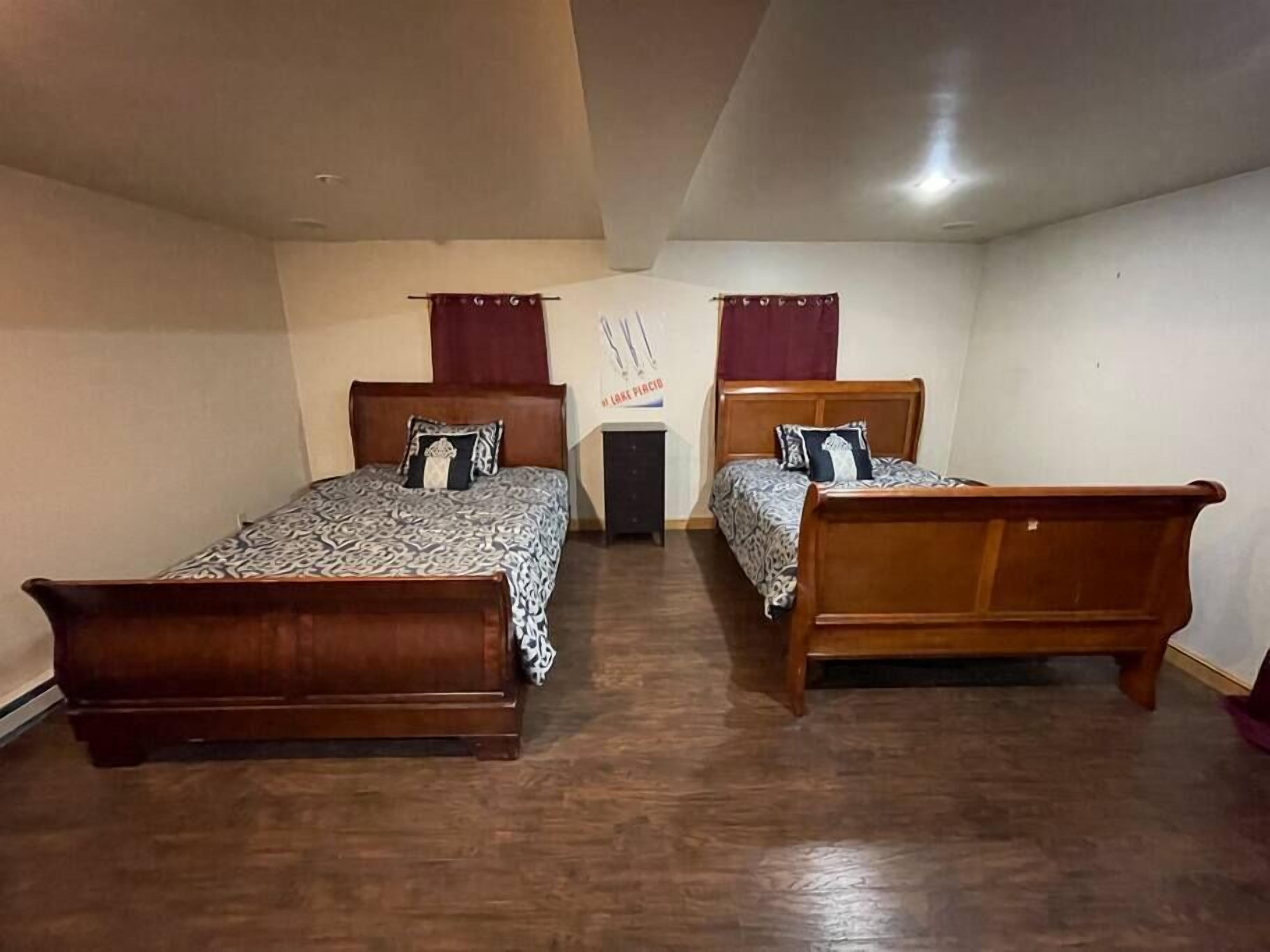 A room with two wooden beds, a small table, and a wall with a poster.