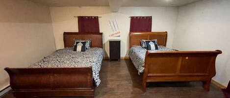 A room with two wooden beds, a small table, and a wall with a poster.