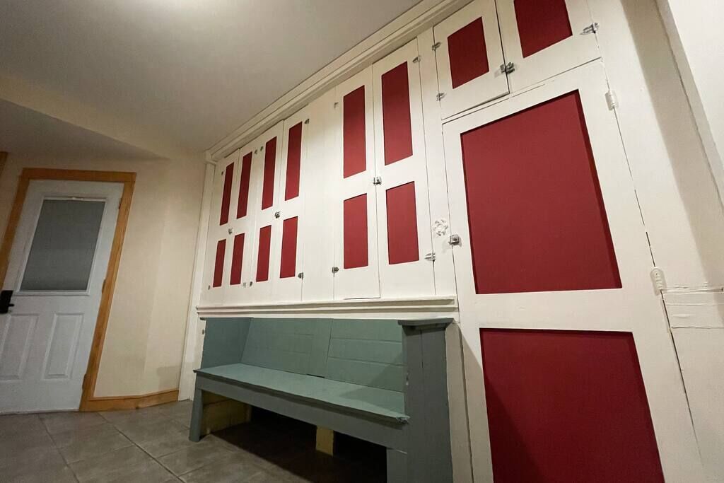 A hallway with a bench, a door, and a row of lockers.