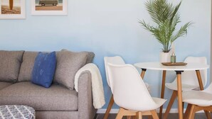 A living room with a grey sofa, white chairs, a small round table, and a potted plant. - Pet friendly | 5 min walk to sand | full kitchen (Myrtle Beach)