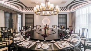 A round dining table set for a meal with a central chandelier, surrounded by chairs. - Dihao International Hotel (Guang'an)