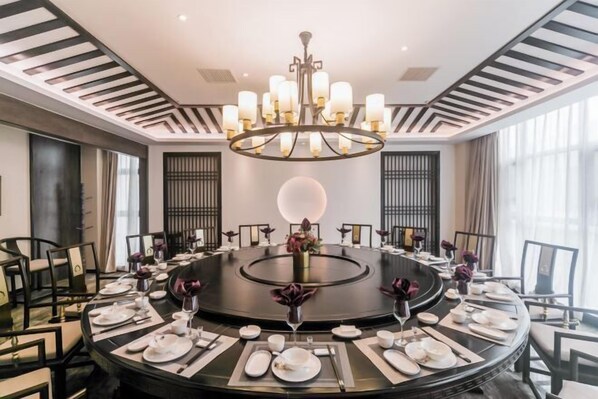 A round dining table set for a meal with a central chandelier, surrounded by chairs. - Dihao International Hotel (Guang'an)