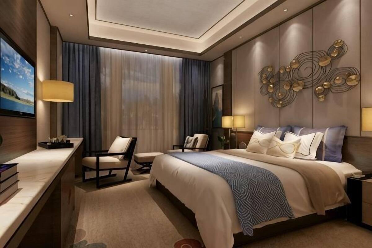 A hotel room with a large bed, a desk, a chair, and a TV.