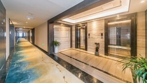 A modern hotel lobby with a marble floor, elevators, and a potted plant. - Dihao International Hotel (Guang'an)
