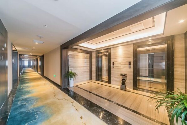 A modern hotel lobby with a marble floor, elevators, and a potted plant. - Dihao International Hotel (Guang'an)