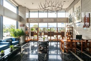 A spacious lobby with a high ceiling, large windows, a central seating area, and a view of the outdoors. - Dihao International Hotel (Guang'an)