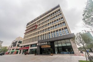 Un edificio de varios pisos con un diseño arquitectónico moderno, que cuenta con una entrada destacada con puertas de vidrio y un letrero en la parte superior.