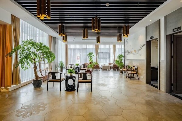A spacious lobby with hexagonal patterned flooring, multiple seating areas, and large potted plants. - Dihao International Hotel (Guang'an)