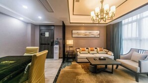 A modern hotel room with a sofa, armchairs, a coffee table, a chandelier, and a large window. - Dihao International Hotel (Guang'an)