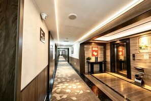 Pasillo de hotel con alfombra estampada, un mostrador de recepción y una cámara de seguridad.