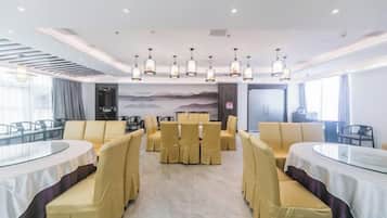 A conference room with round tables and yellow chairs, a large mural on the wall, and a modern ceiling design.
