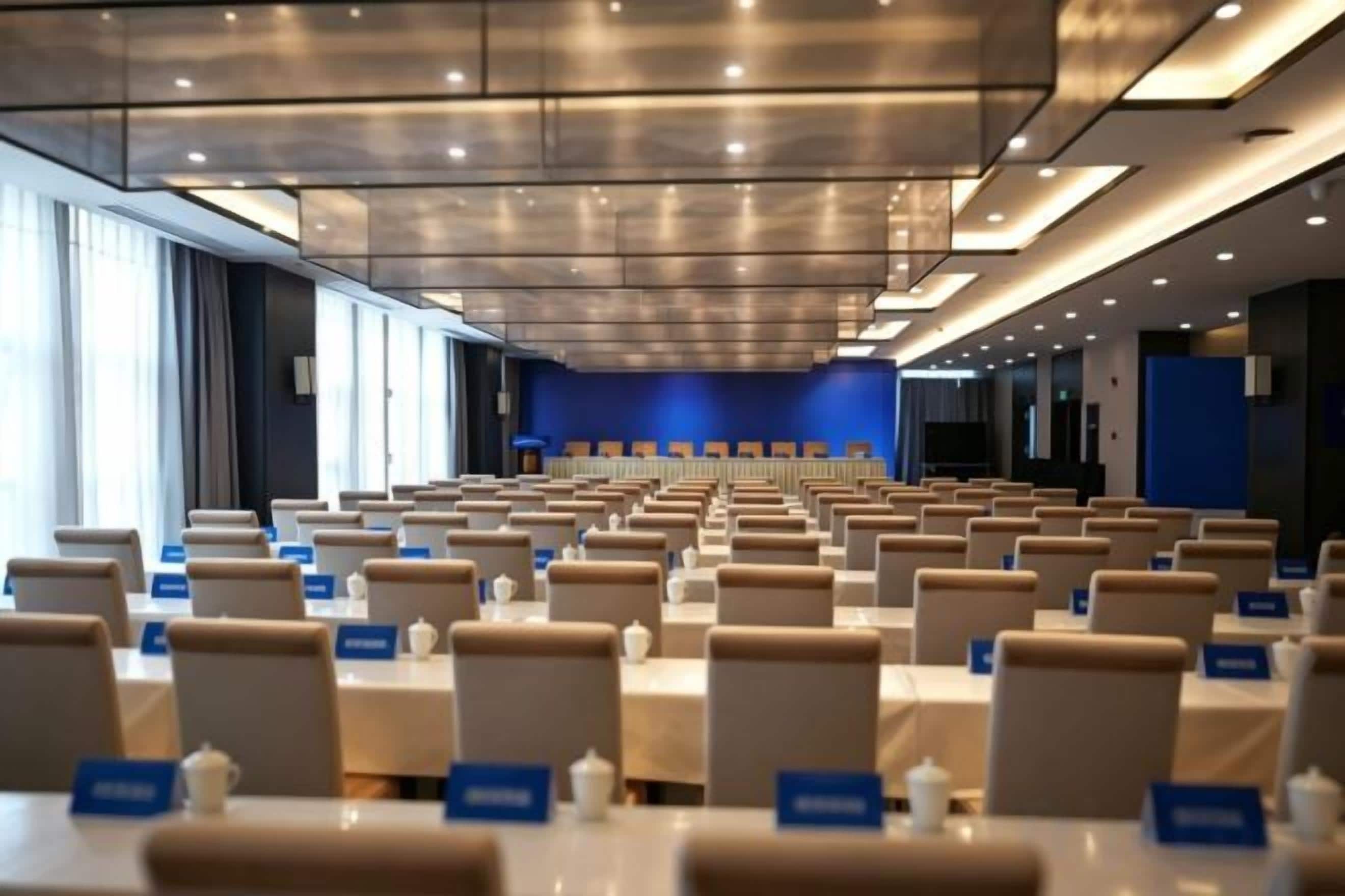 A conference room with rows of tables and chairs, nameplates, and a blue accent wall.