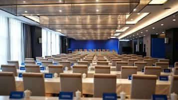 A conference room with rows of tables and chairs, nameplates, and a blue accent wall.