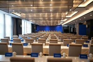 Un salón de conferencias con filas de mesas y sillas, tarjetas de identificación y una pared de acento azul.