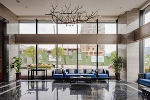 Un vestíbulo moderno con zona de estar, ventanas amplias y suelo reflectante.