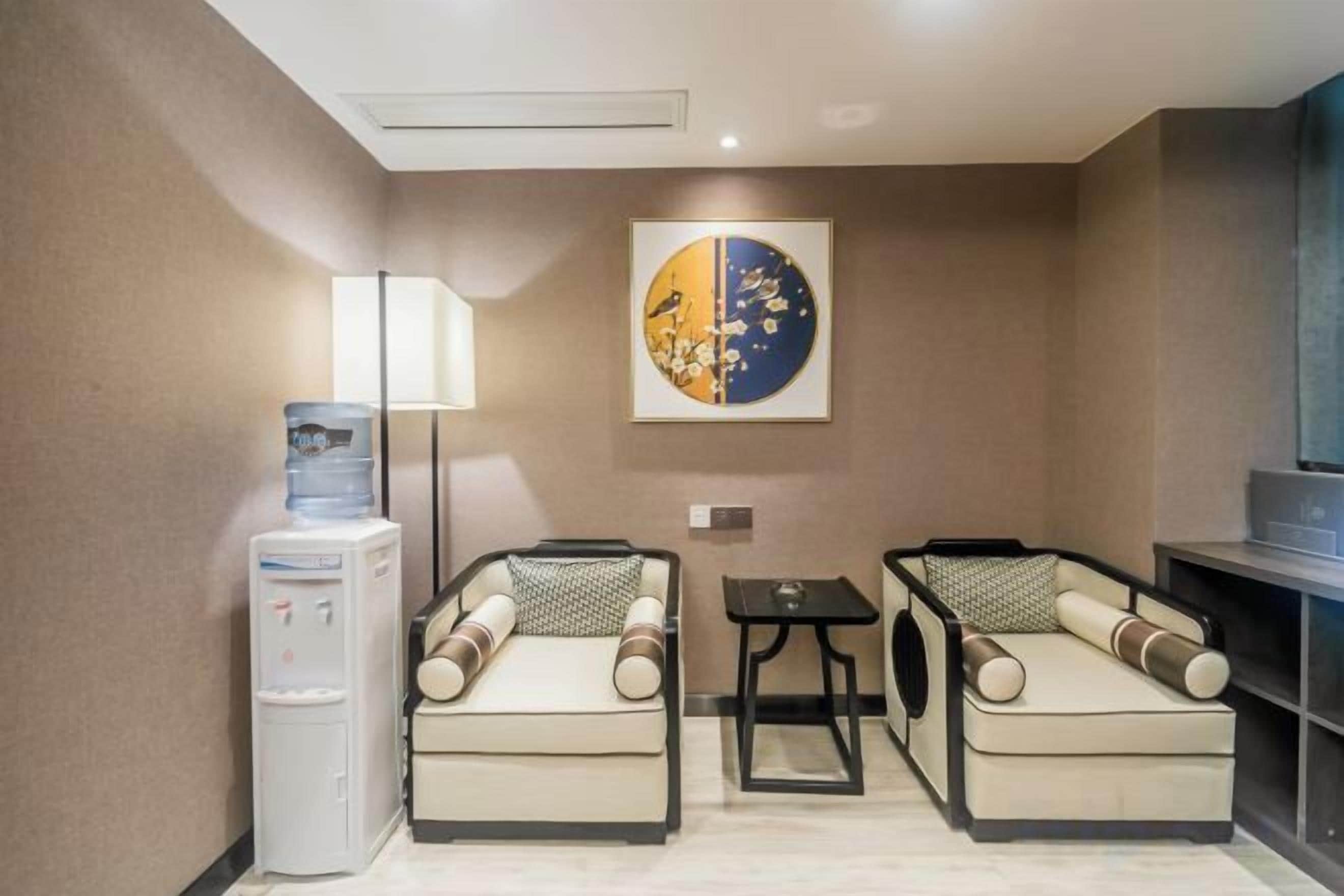 A hotel room with two sofas, a small table, a water dispenser, and a TV.