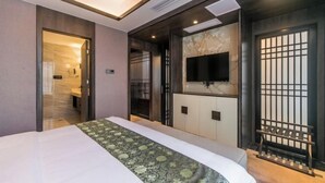 A hotel room with a bed, a TV mounted on the wall, a sliding door, and a small seating area. - Dihao International Hotel (Guang'an)
