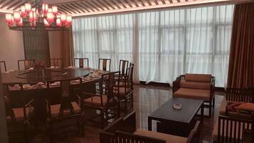 A hotel dining area with a round table, chairs, and a sofa.