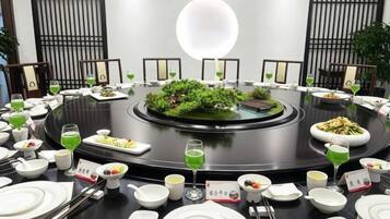 A round dining table with various dishes and drinks, surrounded by chairs.