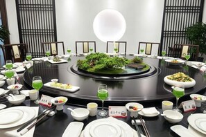 A round dining table with various dishes and drinks, surrounded by chairs.