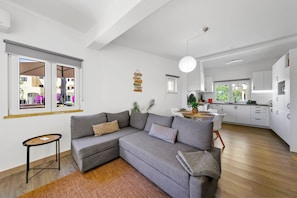 Uma sala de estar moderna com um sofá sectional cinza, uma mesinha de apoio e vista para o exterior pela janela.