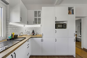 Uma cozinha moderna com armários brancos, micro-ondas e máquina de café.