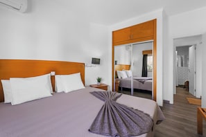 Habitación de hotel con una cama grande, una mesita de noche, un espejo y vistas a otra habitación.