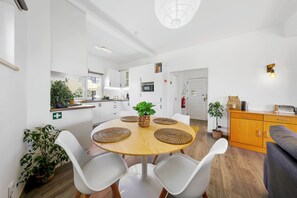 A modern kitchen with white cabinets, a wooden dining table with woven placemats, and a built-in microwave.