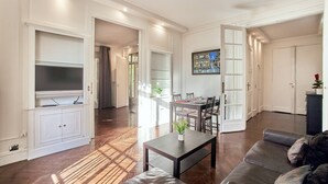 Un salon spacieux avec une grande télévision, un coin repas et un espace salon confortable.