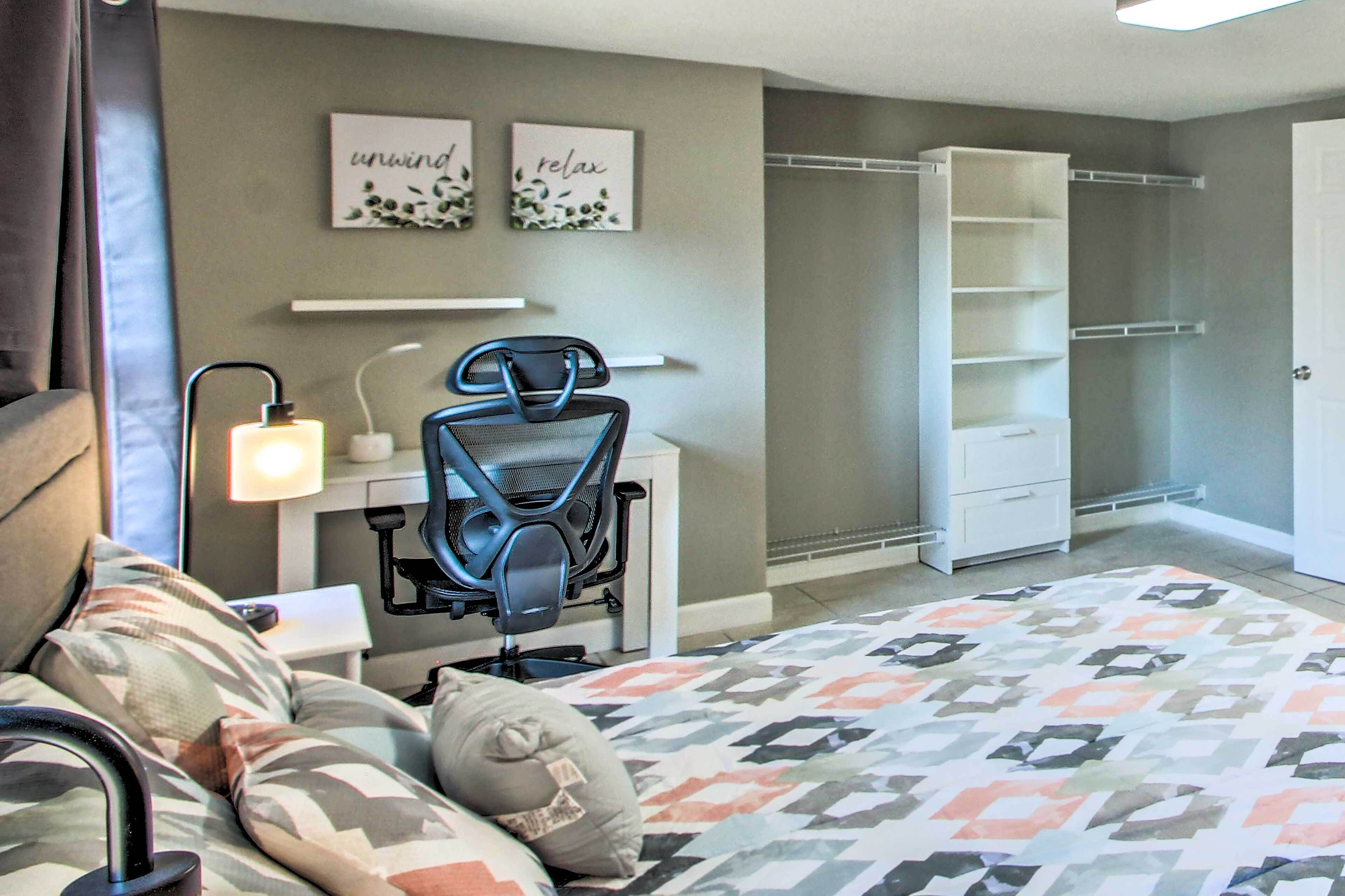 Een slaapkamer met een bed, een bureau met stoel, een kledingkast en wanddecoratie.