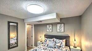 Une chambre à coucher avec un lit, des tables de chevet, un miroir et des œuvres d’art murales.